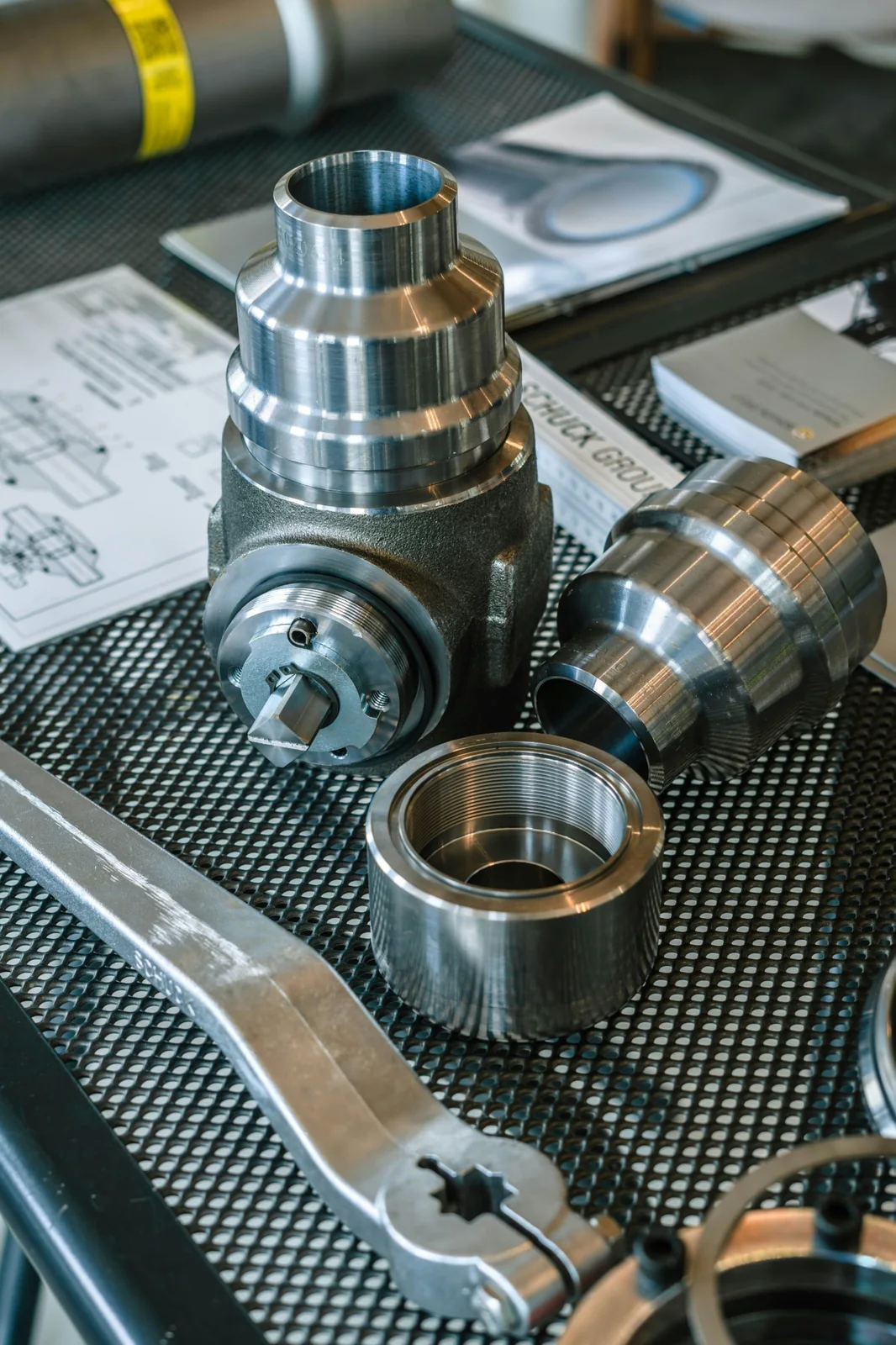 Machined metal components alongside engineering drawings, illustrative photography